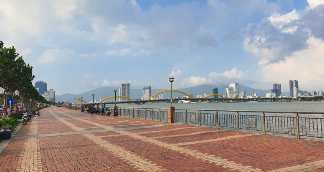 Tiled riverside promenade along the Han River with the Dragon Bridge and city skyline in the distance