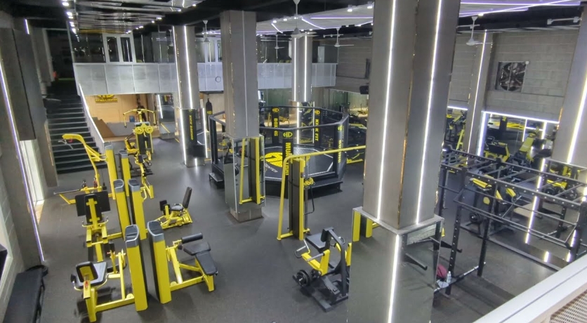 Spacious HD Fitness gym interior with rows of yellow and black weight machines and a boxing ring