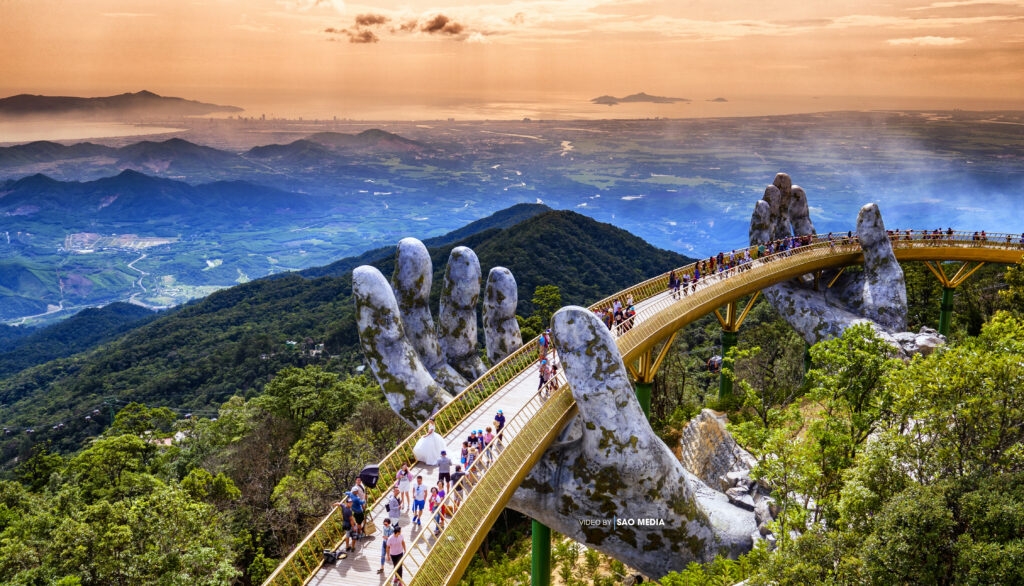 The Golden Bridge held up by two giant stone hands above forested mountains at Ba Na Hills, Da Nang
