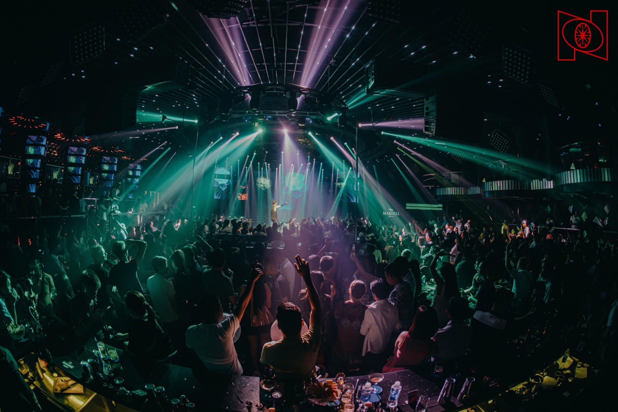 Packed New Phuong Dong nightclub with green and purple laser beams over a crowd facing the stage