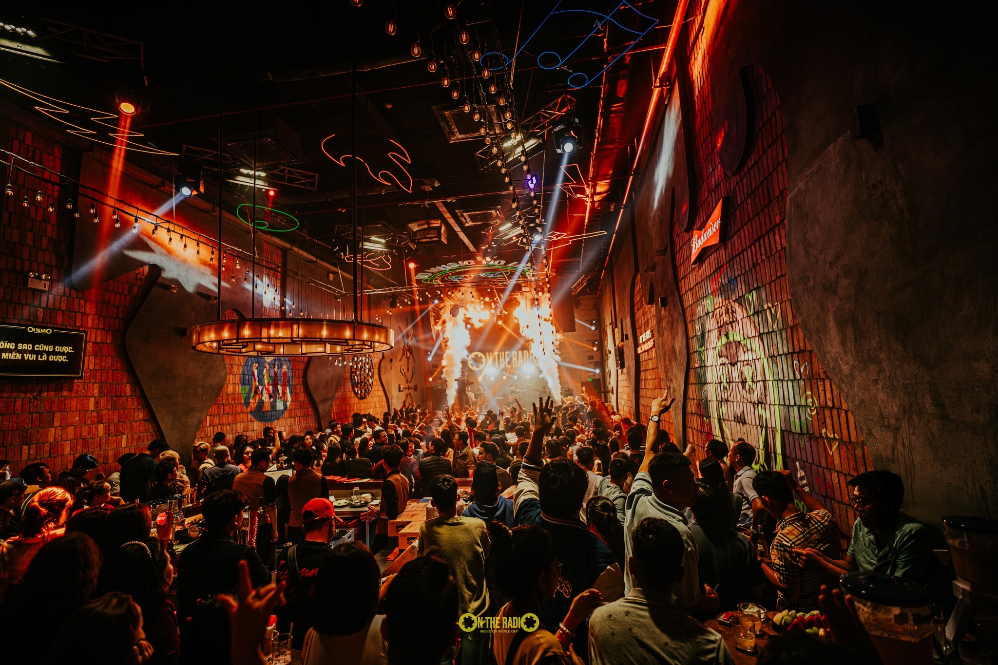 On The Radio bar with brick walls, neon, sparkler fountains and a packed crowd facing the stage