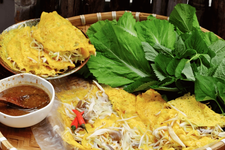 Crispy golden Banh Xeo pancakes with bean sprouts, fresh green herbs and a bowl of brown dipping sauce