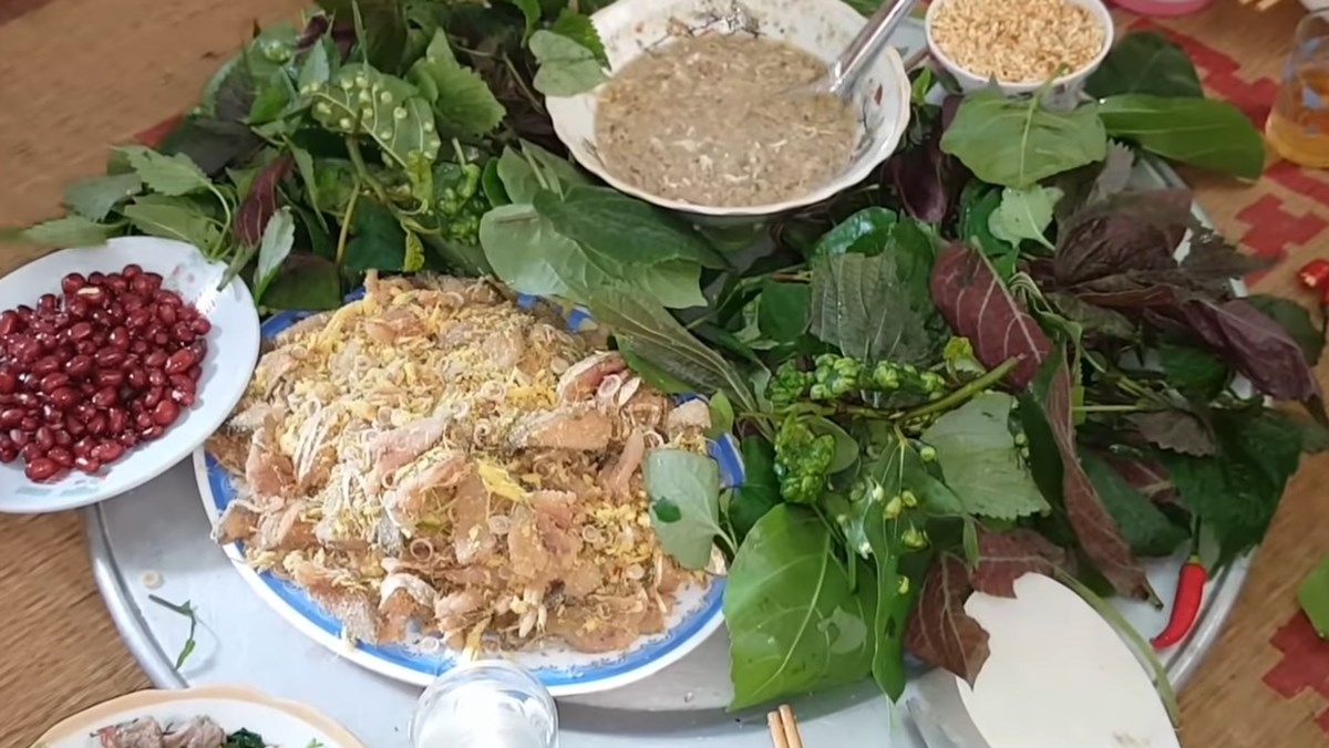 Plate of Goi Ca raw fish salad served with abundant fresh leaves, peanuts and dipping sauce on a tray