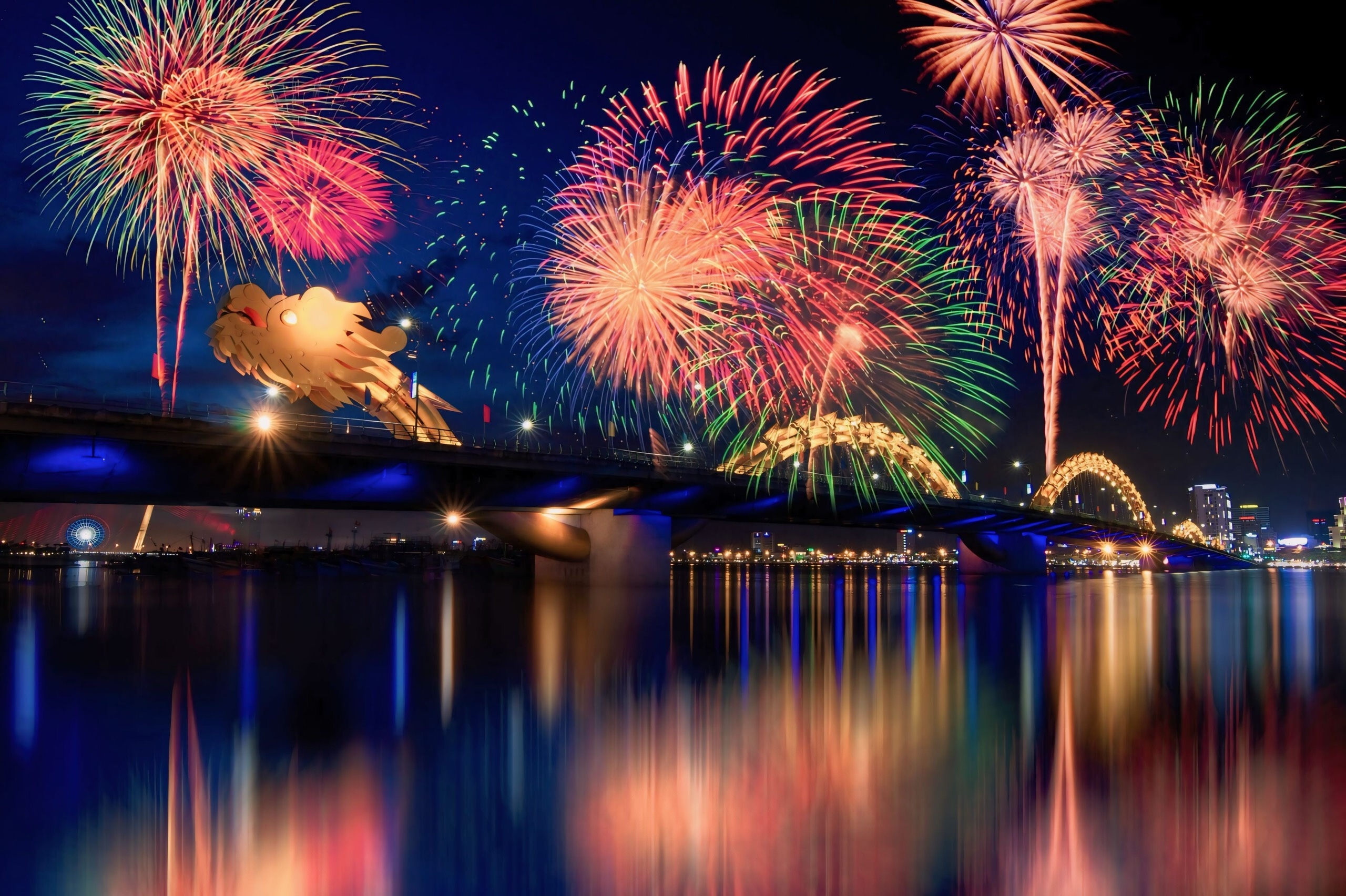 Colorful fireworks over the Dragon Bridge in Da Nang at night, reflected on the Han River below