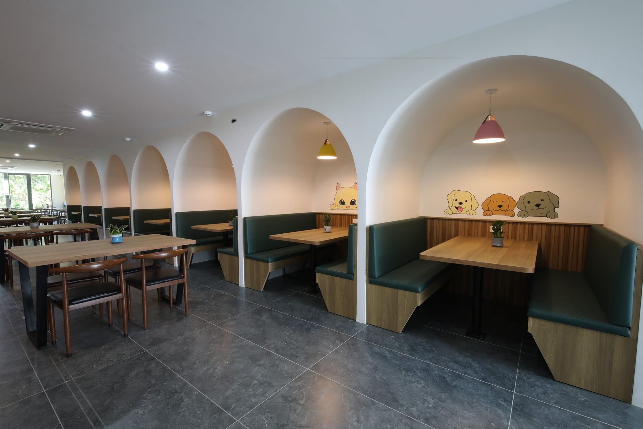 Modern café with arched booth seating, green leather benches, wooden tables and cute cat and dog wall art