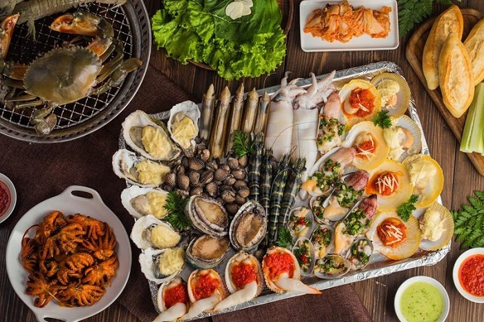 Mixed seafood platter with grilled oysters, scallops, clams, squid and crab on a wooden table