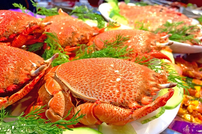 Plate of steamed red crabs garnished with dill and cucumber slices
