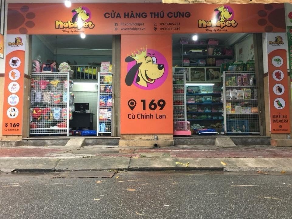 Orange Nobipet pet supermarket storefront with dog mascot signage and shelves of pet supplies in Da Nang