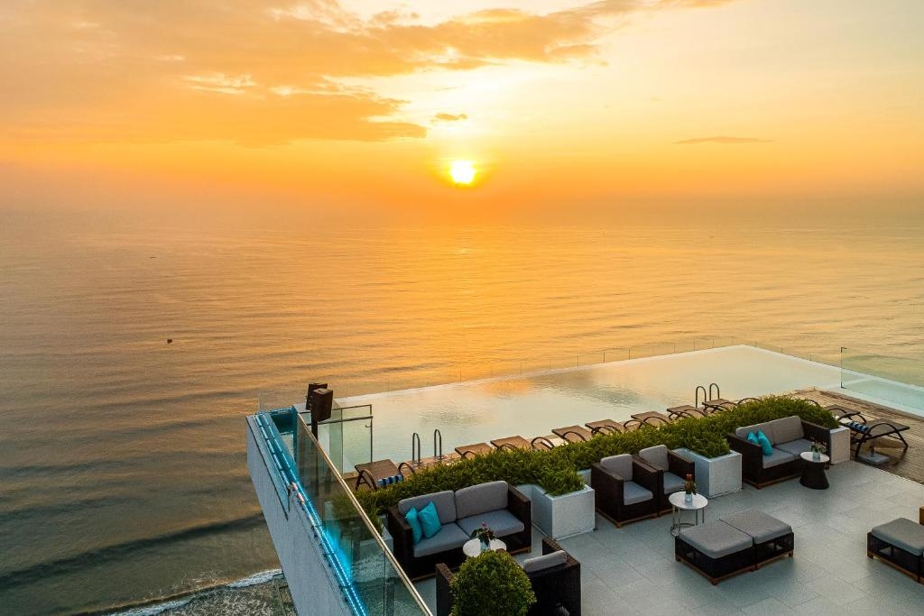 Rooftop infinity pool and outdoor lounge seating overlooking the ocean at sunset
