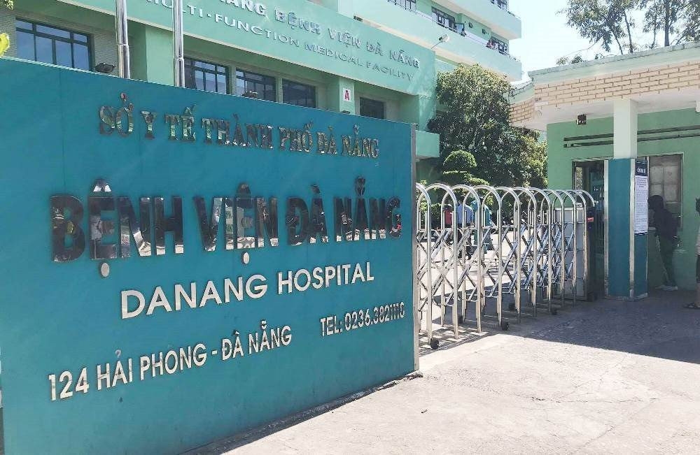Green entrance sign reading Benh Vien Da Nang Danang Hospital at the gated entrance to the hospital building