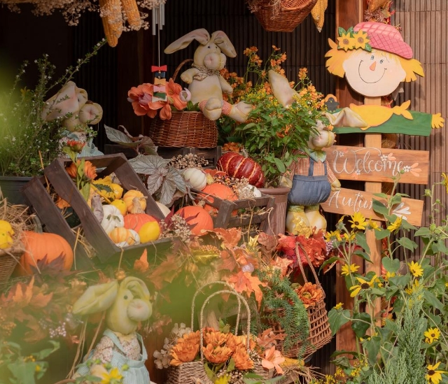 Autumn-themed corner with crates of pumpkins, sunflowers, plush rabbit figures and a Welcome Autumn wooden sign