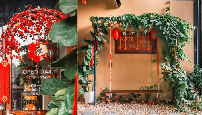 Ante Cafe storefront framed by green foliage and red blossom decorations with a glass door reading Open Daily 7:00 to 22:00